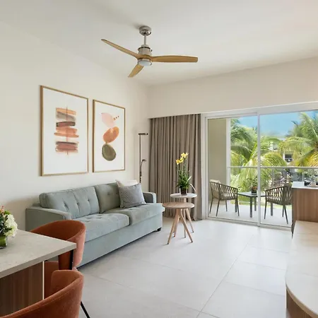 Dreams Royal Beach Punta Cana (Adults Only) Room photo The photo shows a bright and airy living space, likely in a vacation rental or apartment, with a modern and comfortable feel. 

The main area features a light blue sofa with several throw pillows, positioned against a wall adorned with two framed abs