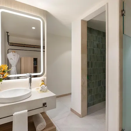 Dreams Royal Beach Punta Cana (Adults Only) Facilities photo The photo shows a modern and bright bathroom. The main focus is a sleek, rectangular mirror with a warm-toned LED light strip around its perimeter, mounted above a white countertop sink. The sink is oval-shaped and sits on a light beige countertop. A