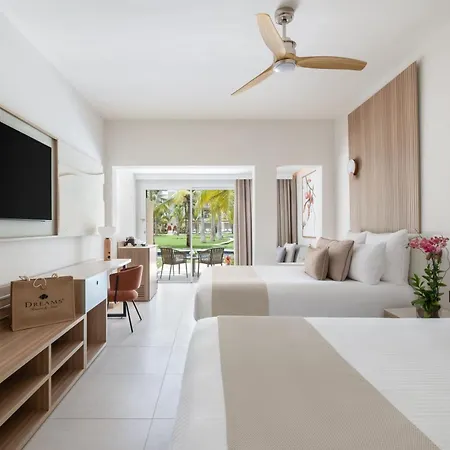 Dreams Royal Beach Punta Cana (Adults Only) Room photo The photo shows a bright and airy hotel room with a modern and minimalist design. The room features two double beds with crisp white linens and beige bed runners. Each bed has several pillows, including standard white pillows and decorative square pi
