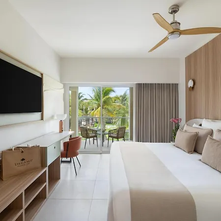 Dreams Royal Beach Punta Cana (Adults Only) Room photo The photo shows a bright and modern hotel room with a comfortable king-sized bed as the focal point. The bed is neatly made with white linens and several plush pillows in varying shades of beige and brown, suggesting a relaxing atmosphere. A soft, be