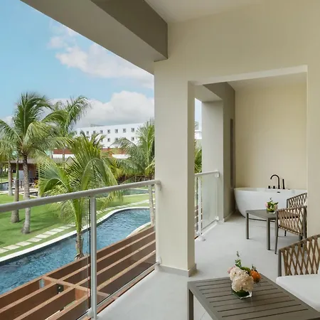 Dreams Royal Beach Punta Cana (Adults Only) Amenities photo The photo shows a luxurious balcony with a stunning view. The balcony is spacious and features a comfortable seating area with two woven armchairs and a small wooden table. 

The balcony overlooks a beautiful outdoor area with a sparkling blue swimmi